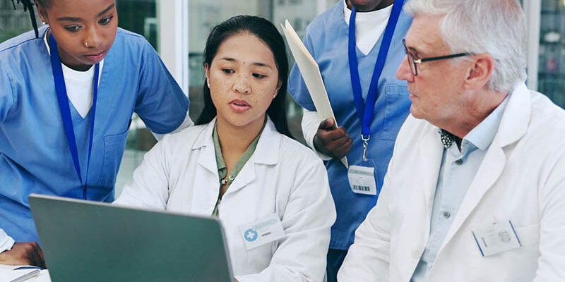 Doctors and nurses looking at laptop and talking among each other.